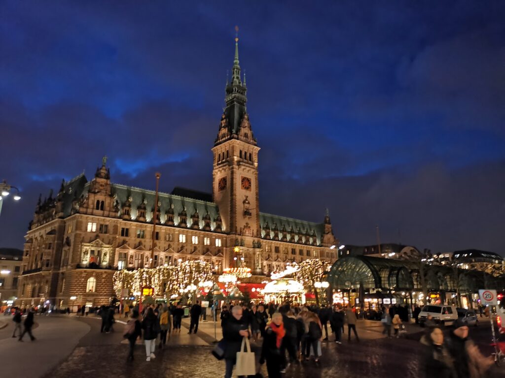 Beleuchtetes Hamburger Rathaus mit Weihnachtsmarkt bei Dunkelheit